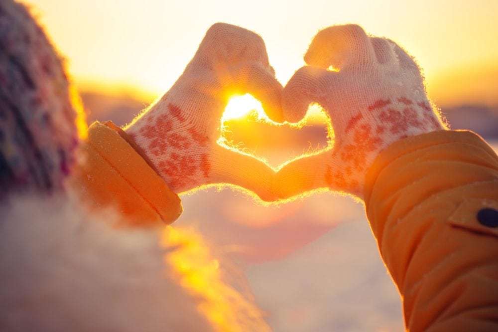 Woman making a heart shape with her gloved hands in winter